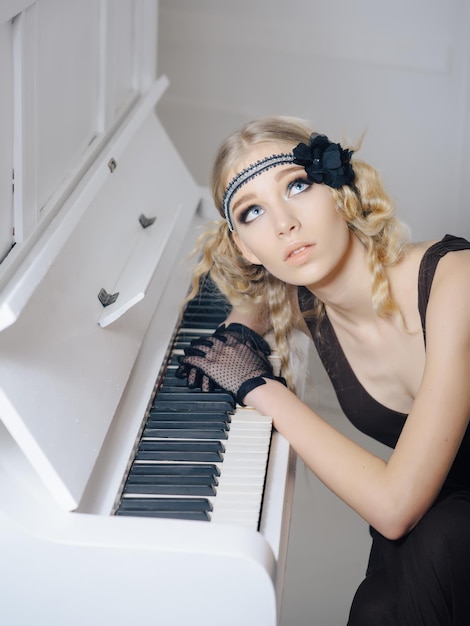하얀 피아노의 열린 키보드에 누워 있는 동안 올려다 보는 파란 눈을 가진 젊은 여배우