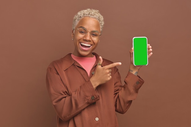 Young admiring ethnic african american woman holding phone with green screen