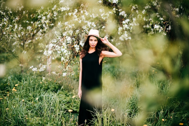 Young adorable  brunette woman in black dress in spring blooming garden