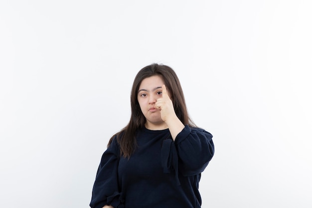 young adorable girl with down syndrome standing and pointing.