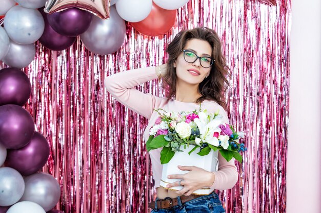 Young adult beautiful and happy woman model holding flowers portrait on festive background