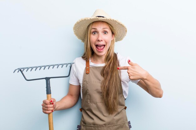 熊手を持つ若い大人のブロンドの女性の農夫