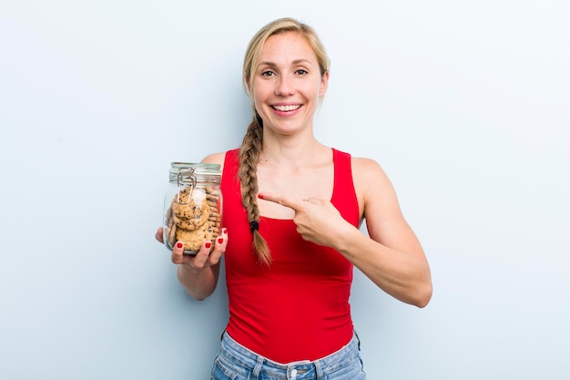 Young adult blonde woman with home made cookies bottle