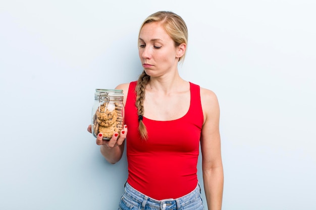 Young adult blonde woman with home made cookies bottle