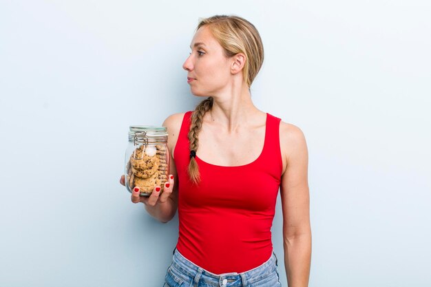 Young adult blonde woman with home made cookies bottle