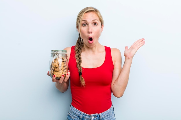 Young adult blonde woman with home made cookies bottle