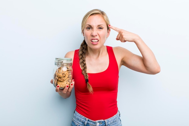 Young adult blonde woman with home made cookies bottle