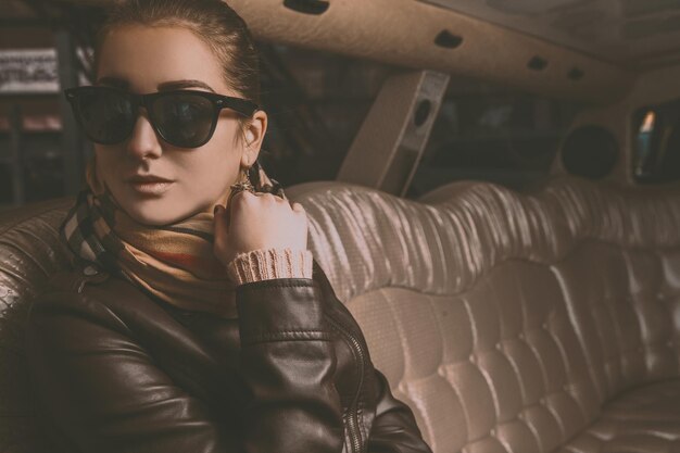 Young adult brunette girl looking away in limousine in retro tones