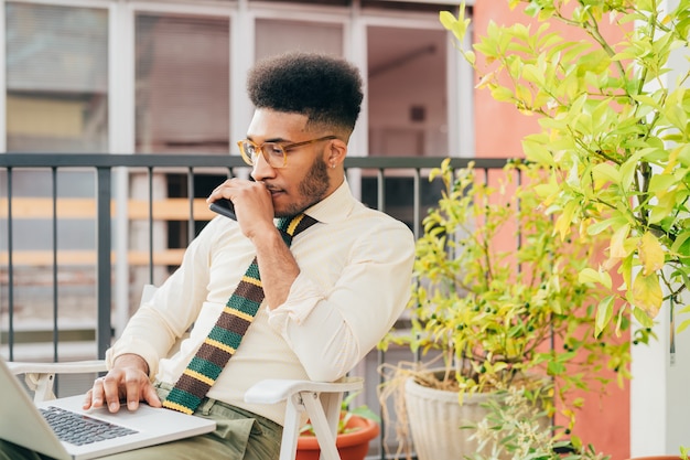 Lavoro astuto del giovane uomo adulto di affari all'aperto facendo uso del computer