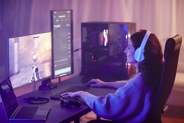 Young adult caucasian woman spending free time playing shooter video game on desktop computer in liv