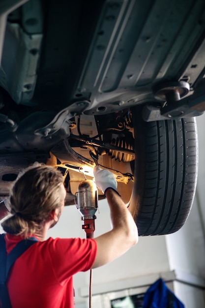 Young adult confident man in work uniform working on cars