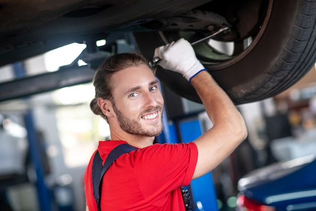 Young adult confident man in work uniform working on cars