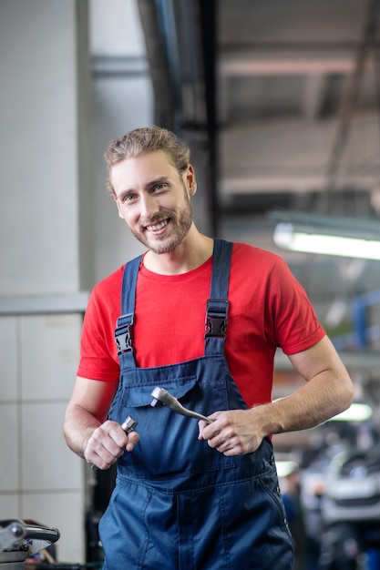 車に取り組んで作業服の若い大人の自信を持って男