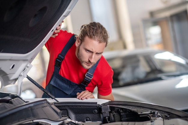 Young adult confident man in work uniform working on cars