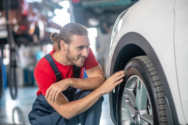 Young adult confident man in work uniform working on cars