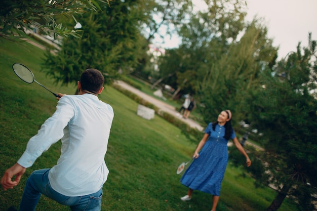 Young adult couple playing badminton in the park.