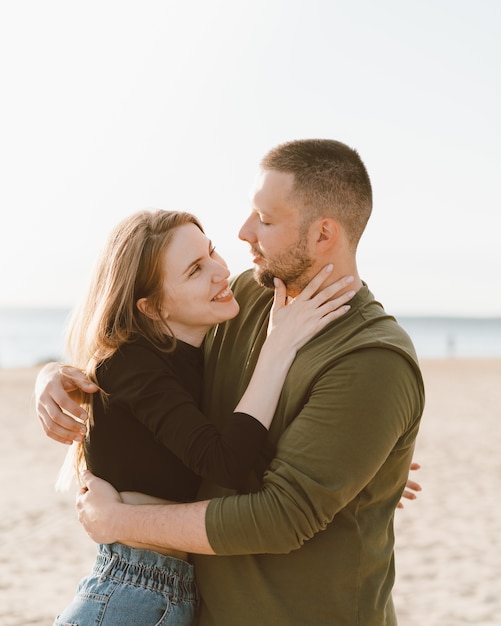 Young adult couple standing on beach, looking each other.