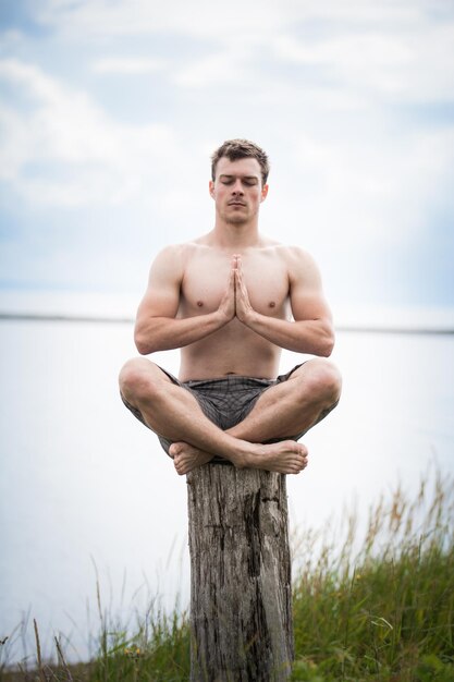 Giovane adulto che fa yoga su un ceppo in natura