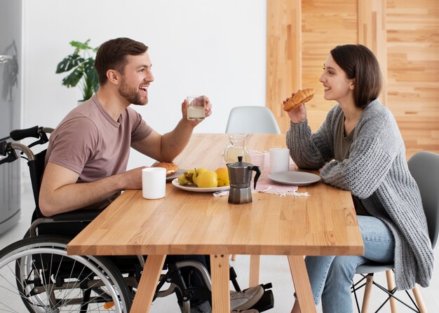 Young adult eating with disabled friend