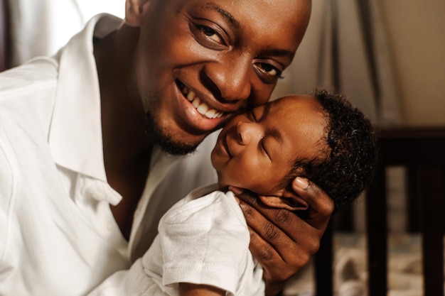 Young adult father smiling holding his newborn son