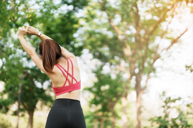 사진 공원 야외 스포츠 여성에서 근육을 스트레칭하는 분홍색 운동복을 입은 젊은 성인 여성은 아침 건강 운동과 직장 생활 균형 개념에서 달리기와 조깅을 할 준비를 합니다.