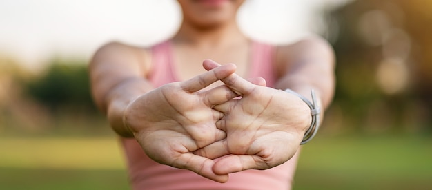 Young adult female in pink sportswear stretching muscle in the park outdoor.