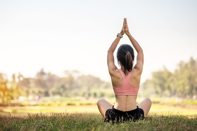 Giovane femmina adulta in abiti sportivi che fa yoga nel parco all'aperto.