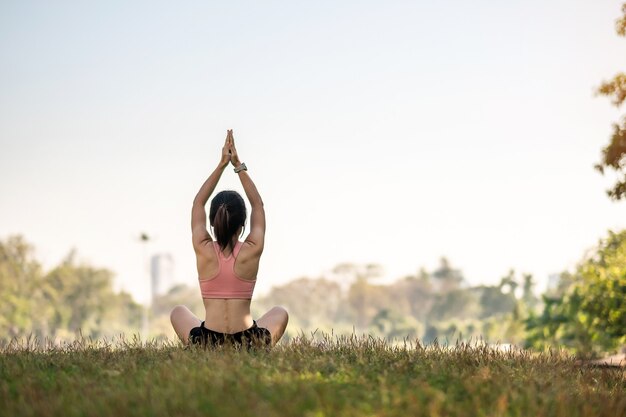 Giovane femmina adulta in abiti sportivi che fa yoga nel parco all'aperto.