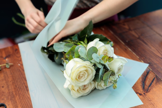 젊은 성인 소녀 꽃집은 흰 장미 꽃다발을 만듭니다. 근접 사진입니다.