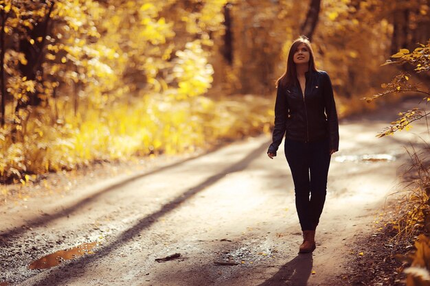 Young adult girl portrait in autumn park yellow leaves background