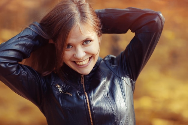 Young adult girl portrait in autumn park yellow leaves background