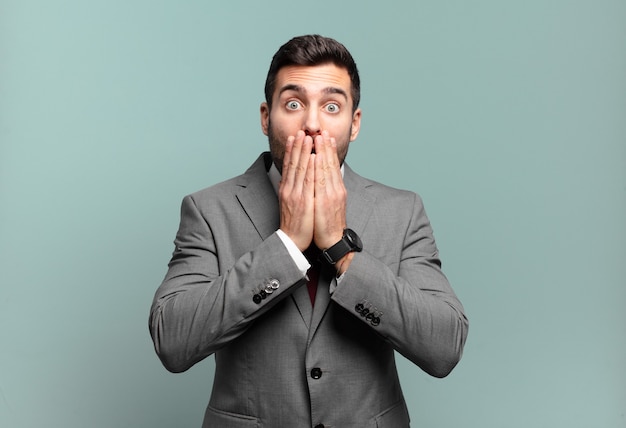 Young adult handsome businessman feeling worried, upset and scared, covering mouth with hands, looking anxious and having messed up