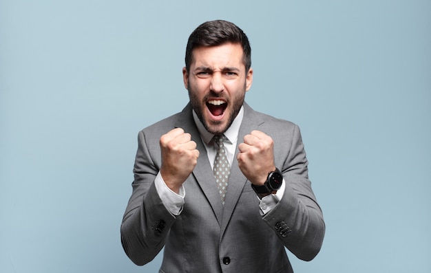 Young adult handsome businessman shouting aggressively with annoyed