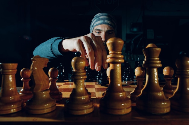 Young adult handsome man playing chess in dark with side lit