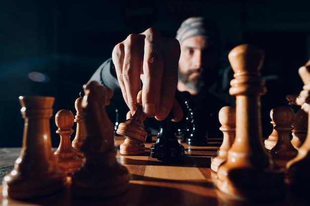 Young adult handsome man playing chess in dark with side lit