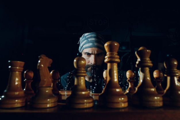 Young adult handsome man playing chess in dark with side lit