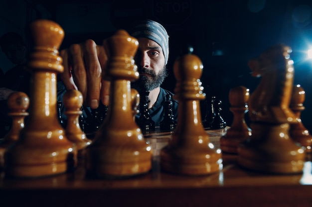 Young adult handsome man playing chess in dark with side lit