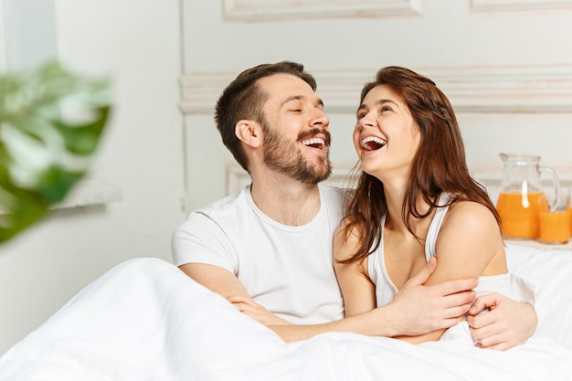 Young adult heterosexual couple lying on bed in bedroom