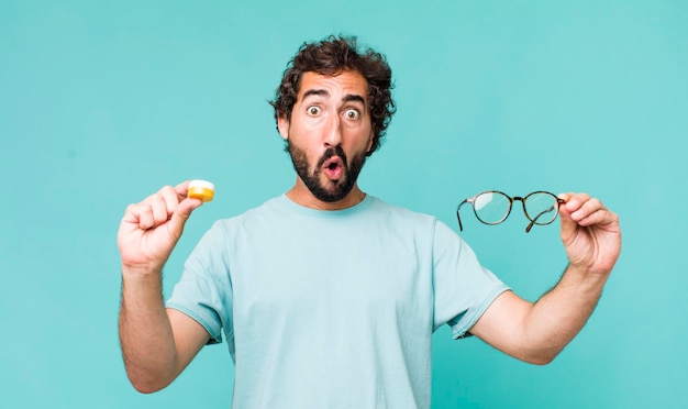 Young adult hispanic crazy man choosing between glasses or\
contact lens