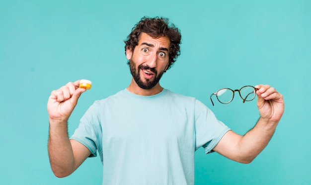 Young adult hispanic crazy man choosing between glasses or\
contact lens