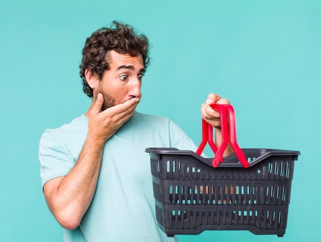 Young adult hispanic crazy man empty shopping basket concept