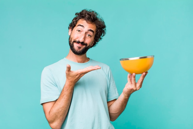 Young adult hispanic crazy man holding an empty bowl