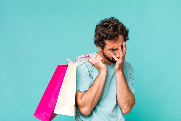 Young adult hispanic crazy man shopping bags concept