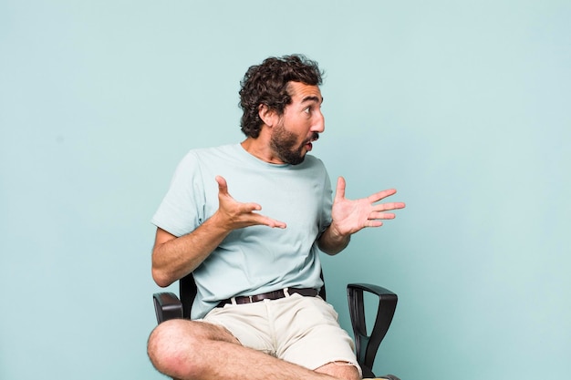 Young adult hispanic crazy man sitting on a chair