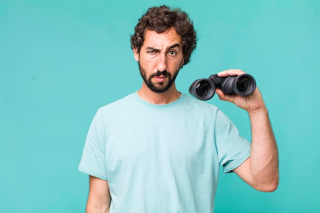 Young adult hispanic crazy man with binoculars searching concept