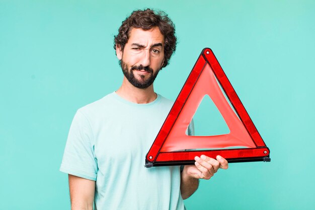 Young adult hispanic crazy man with a car emergency triangle