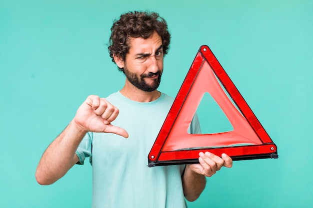 Young adult hispanic crazy man with a car emergency triangle