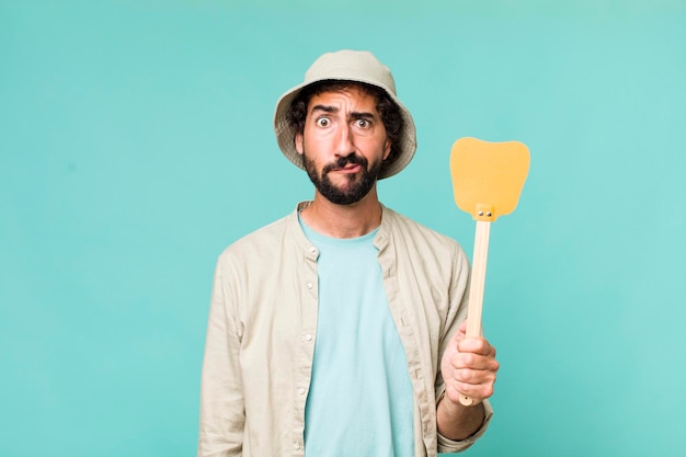 Young adult hispanic crazy man with a fly swatter