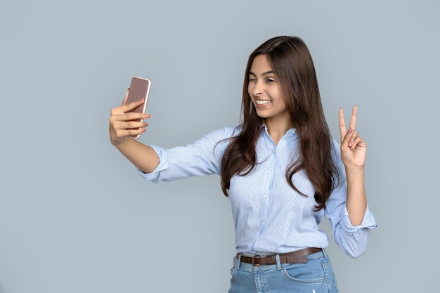 Young adult indian woman making selfie on smart phone