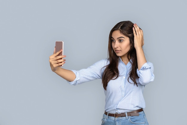 Young adult indian woman making selfie on smartphone